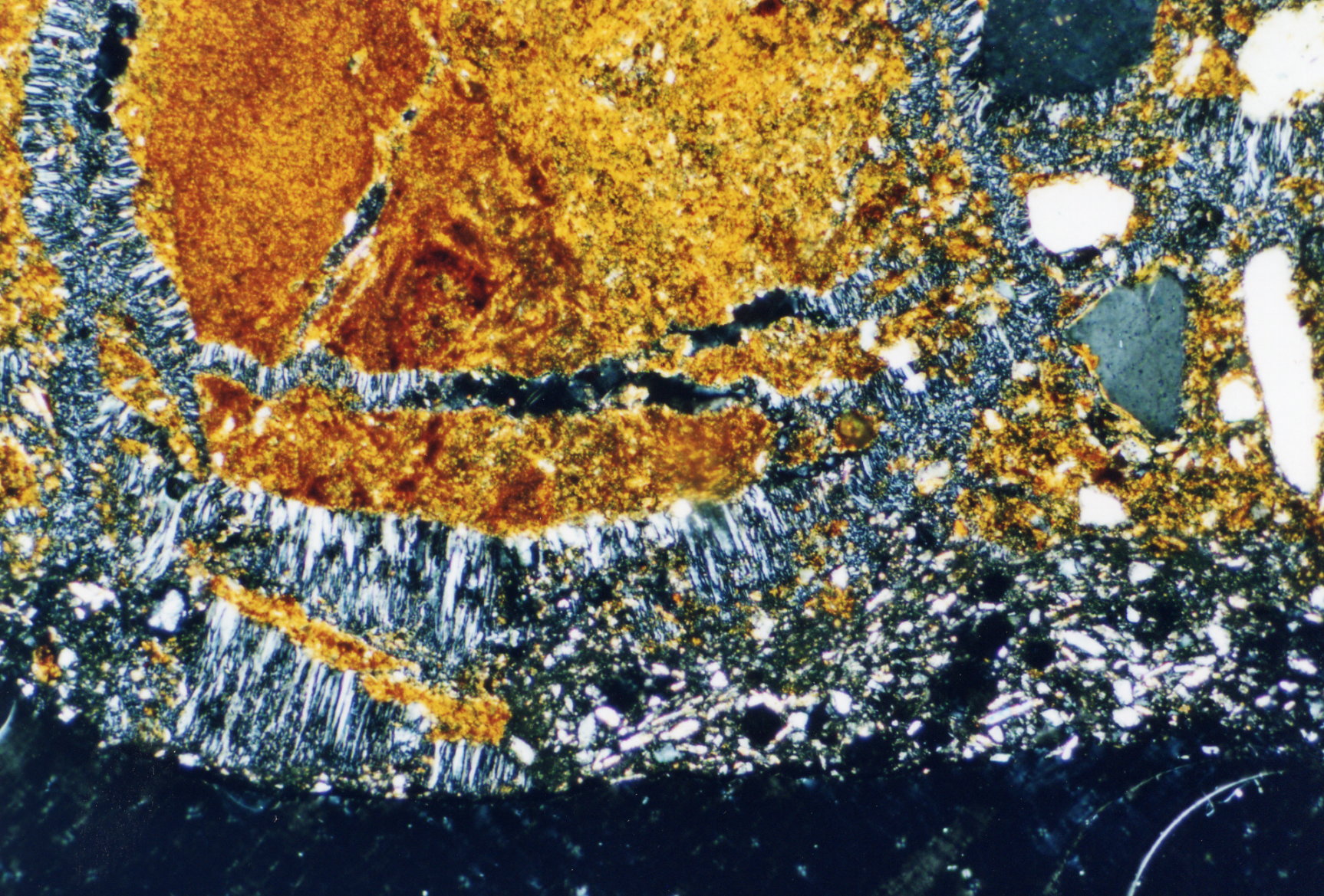Figure 3: Photomicrograph as Fig 2 but with crossed polarisers. It is clearly seen that the plaster is both responsible for the damage and on the other hand, he acts in this case as a kind of glue that holds together the broken brick pieces. With the removal of the original plaster the brick material would be lost.